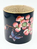 Front view showing plum blossom cluster and butterfly on black enamel, brass rim visible