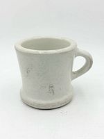 Side view of white ironstone shaving mug showing handle and general wear
