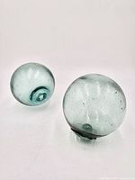 Two seafoam green glass fishing floats side by side