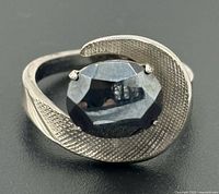 Front view of ring showing faceted hematite stone and modernist swirl setting