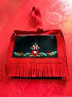 Front view showing embroidered tulip motif, red fringe and strap