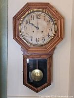 Full view of oak regulator wall clock hanging on wall