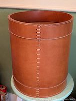 Full view of cylindrical leather basket showing stitching and size