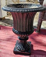 Full view of black cast iron urn on red mat