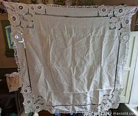 Full view of square lace table topper held up