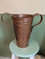 Front view of copper vase showing handles and tapered body