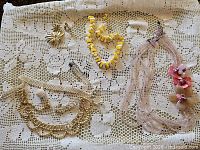 Full lot overview on lace cloth showing all jewellery and perfume bottle