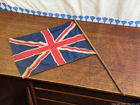 Full view of Union Jack flag on wooden dowel resting on wooden surface