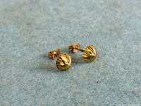 Pair of yellow gold faceted ball stud earrings with butterfly backs on blue surface