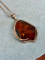 Close view of amber pendant showing cabochon, silver bezel and accent