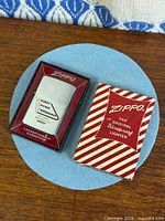 Zippo lighter in display case beside outer sleeve