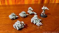 Six unpainted pewter Warhammer 40k miniatures on wooden surface