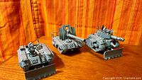 Three painted Leman Russ tanks on wood surface
