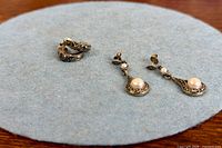 Both pairs of earrings on fabric pad