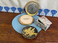 Open gold-tone compact, brass ring tray, marble box group shot