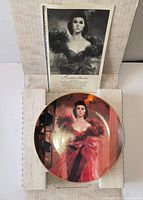Plate in open shipping box showing image of Scarlett O’Hara, information card visible