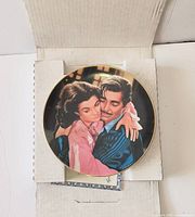 Plate in opened box showing Scarlett and Rhett image, paperwork partially visible