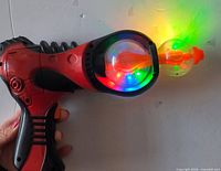 Side view of red and black space gun showing illuminated spinning dome and LEDs