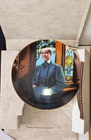 Plate in original packaging showing portrait artwork and gold rim