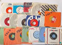 Group shot of twenty 7-inch 45 rpm records in assorted company paper sleeves