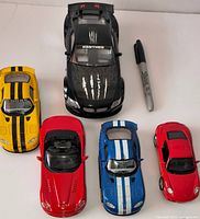 Top view of five model cars with marker for scale