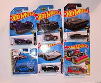 Front view of all six sealed Hot Wheels cars showing card art and vehicle colours