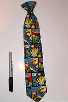 Full view of Marvel comic-print clip-on necktie next to marker for scale