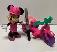 Minnie Mouse figure standing next to pink tricycle accessory with Sharpie shown for scale