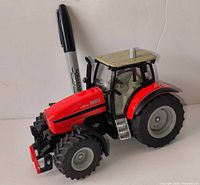 Side view of red Siku tractor with marker for scale