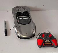 Front view of silver RC Porsche car with remote controller and scale reference