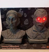 Front view of both busts in box showing detail and red LED eyes lit on male figure