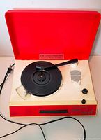 Record player with lid open showing platter, tonearm, speaker and controls