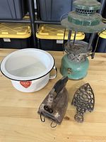 Group shot showing lantern, enamel pot, iron, trivet on table
