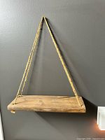 One shelf hanging on wall showing overall appearance and rope hanger