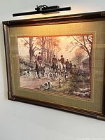 Front view of framed hunting scene print under display light