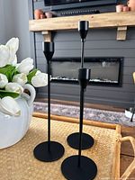 Three black candlestick holders on tray with flowers, showing design