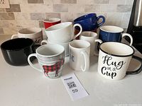 All 12 mugs grouped on countertop showing colours, prints and shapes
