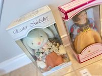 Boxed plush bunny and porcelain doll side by side