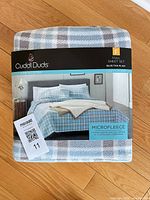 Factory-sealed Cuddl Duds full microfleece sheet set with blue and tan plaid print visible on packaging
