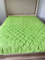 Green side of full/double quilt on bed
