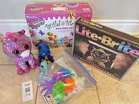 All items grouped: Lite-Brite boxed set, Build & Bloom boxed set, sequin unicorn plush, blue dinosaur plush, bag of fuzzy craft balls