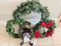 Three wreaths grouped: decorated large evergreen, plain evergreen, grapevine with snowman