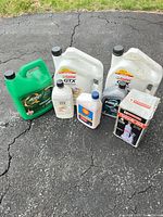 Group shot of all motor oil containers and boxed jack on driveway