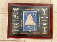 Front view of entire shadow box showing sailboat model, rope knots, labels and wood frame