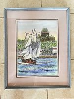 Framed signed print showing sailing ship and cityscape in silver frame with pink mat