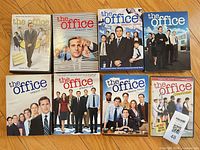 Eight The Office DVD season sets arranged on wood surface showing front covers