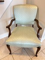 Front view of sage green upholstered accent armchair highlighting fabric, wooden arms, and cabriole legs