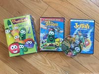 Three VeggieTales DVD cases and one loose VeggieTales disc displayed on wooden floor