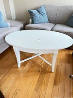 Full view of white oval coffee table between sofas showing entire structure