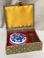 Open box showing porcelain ink container and seal stamp in red velvet compartment